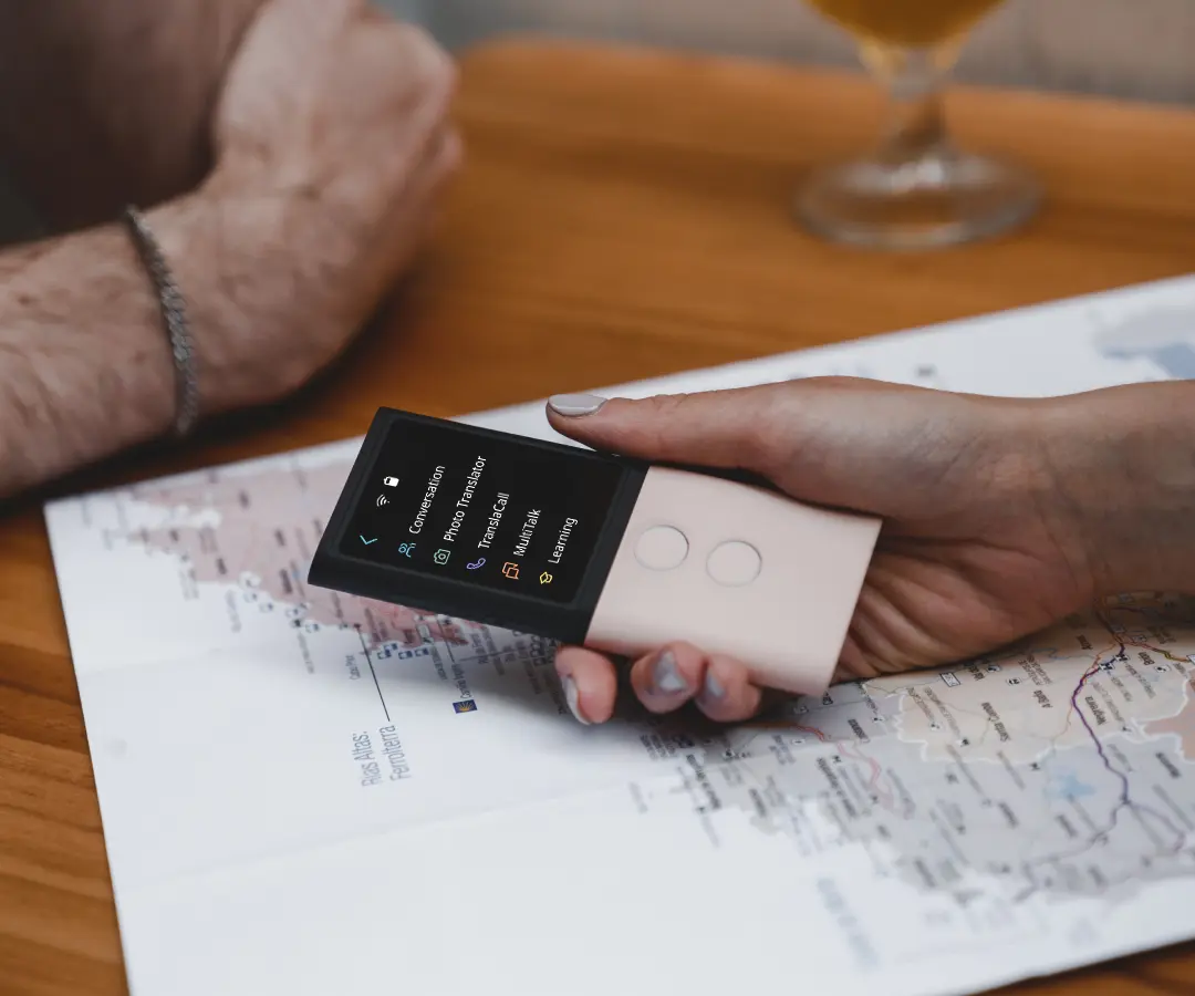 Prim-plan al unei mâini care ține un traducător deasupra unei mese cu o hartă pe ea